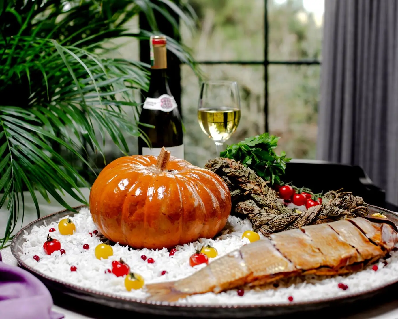 Ein rundes Tablett aus Kupfer mit Reis, Fisch, Kürbis und Kirschtomaten.